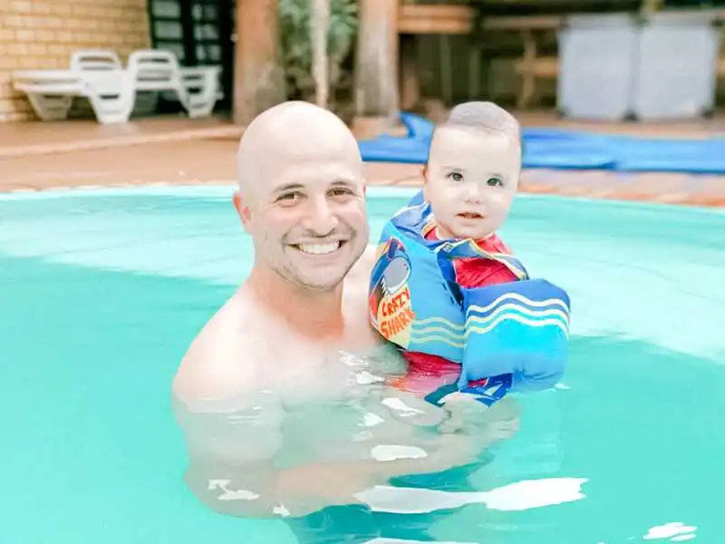 Pai com bebê usando Colete salva-vidas em piscina