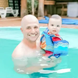 Pai com bebê usando Colete salva-vidas em piscina